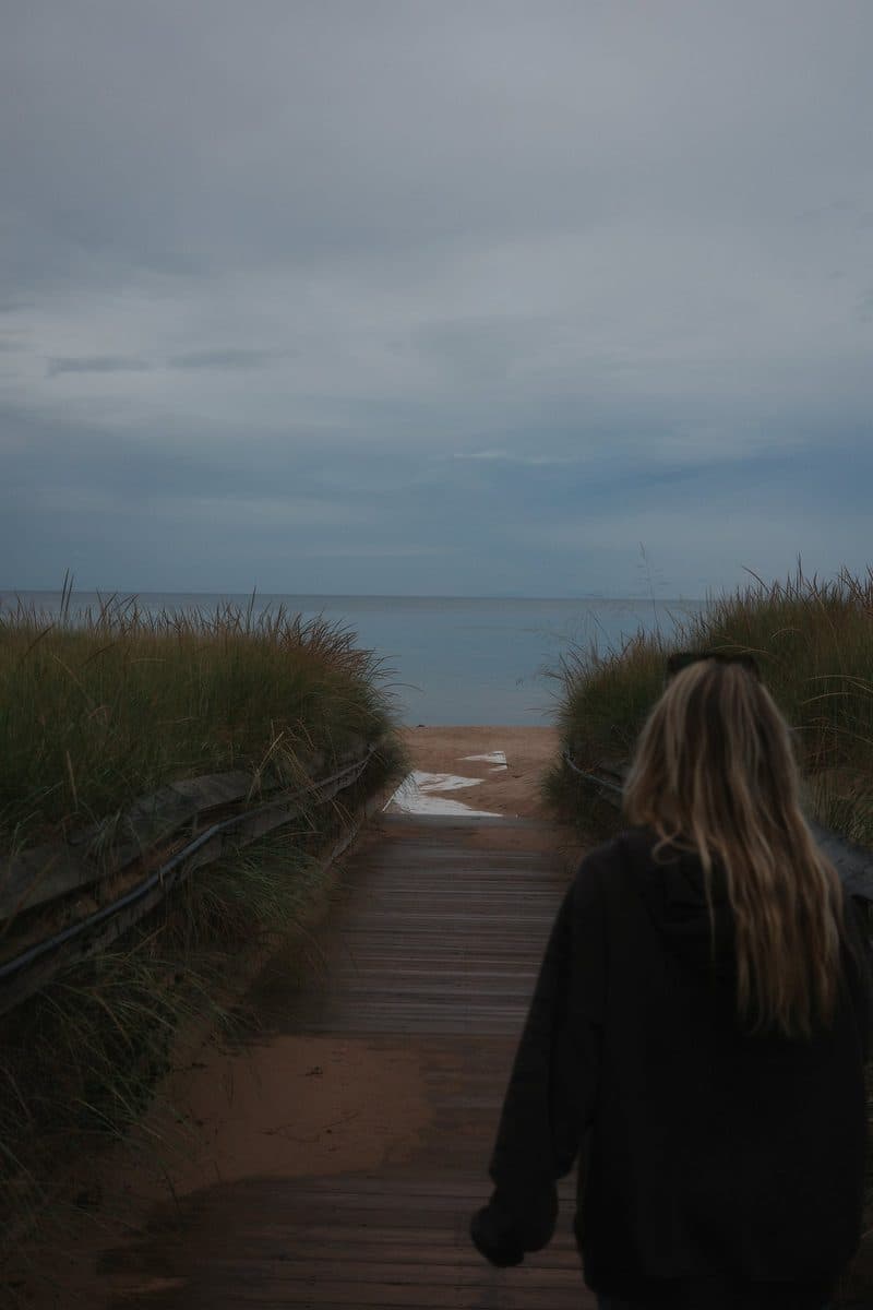 A woman walks ahead on a boardwalk to the lake